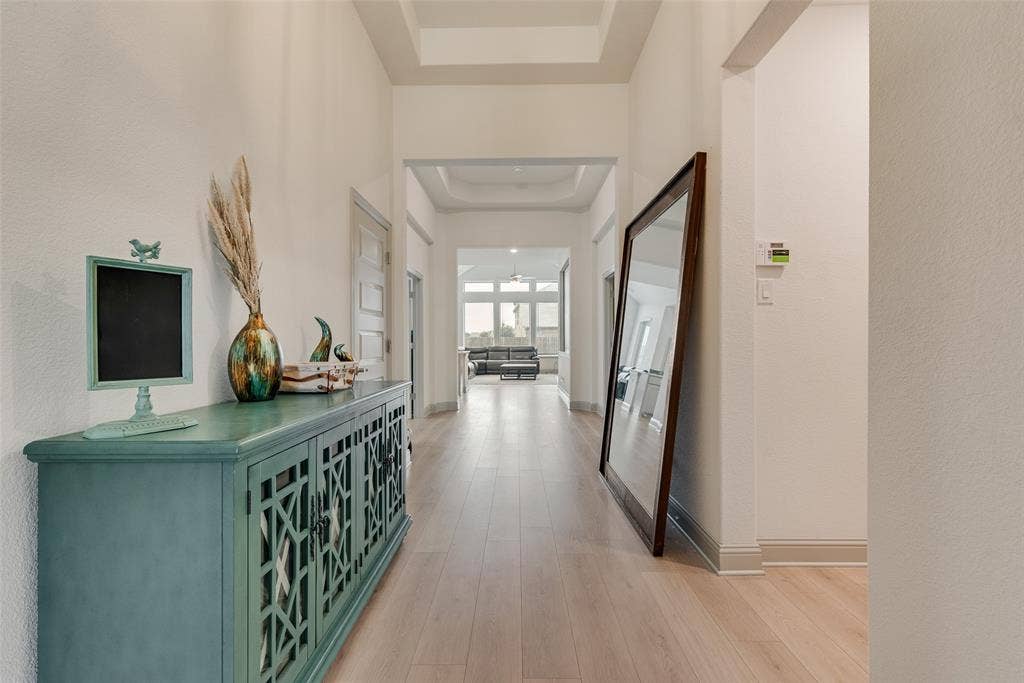 107 White Sands Lane, Forney, TX 75126 Long hallway with wood-finish flooring, tray ceiling, and neutral wall tones