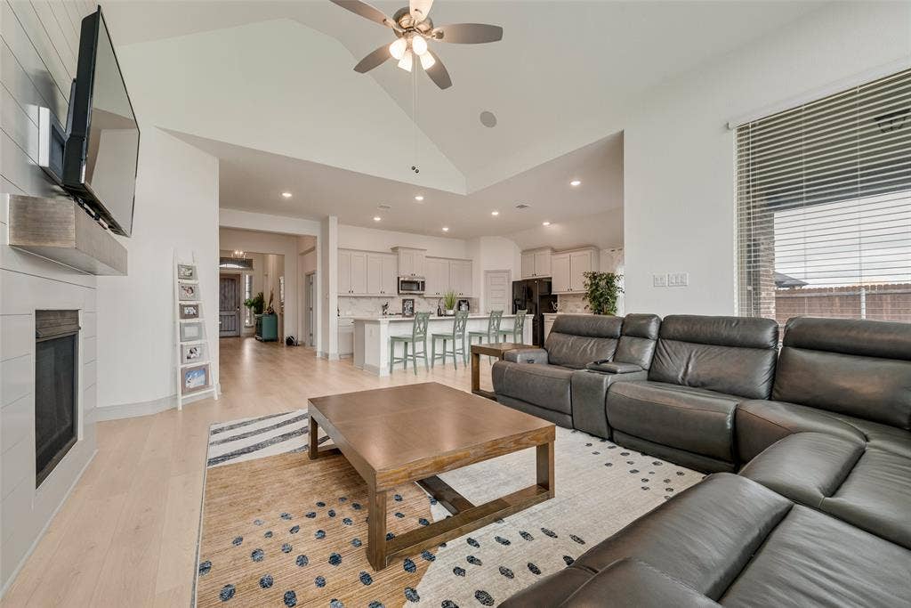 107 White Sands Lane, Forney, TX 75126 Vaulted ceiling with a ceiling fan, light wood-finish flooring, and a fireplace with shiplap-style surround and wood mantel