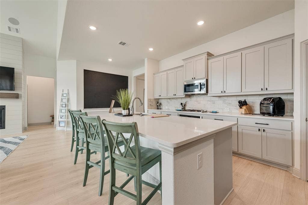 107 White Sands Lane, Forney, TX 75126 Spacious kitchen island with a light-toned countertop, light-toned cabinetry, stainless steel appliances, and wood-finish flooring