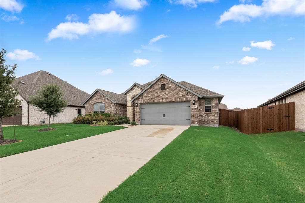 107 White Sands Lane, Forney, TX 75126 Brick exterior, attached garage, concrete driveway, front landscaping, and wood privacy fence