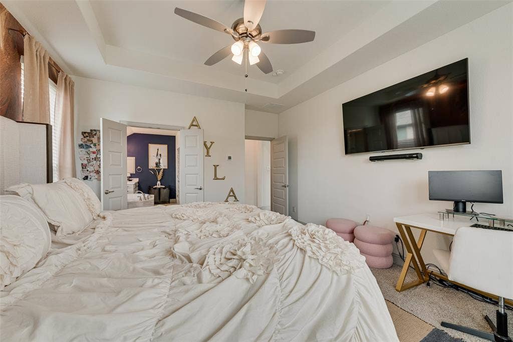 107 White Sands Lane, Forney, TX 75126 Primary bedroom with a tray ceiling and ceiling fan; view toward the ensuite bathroom