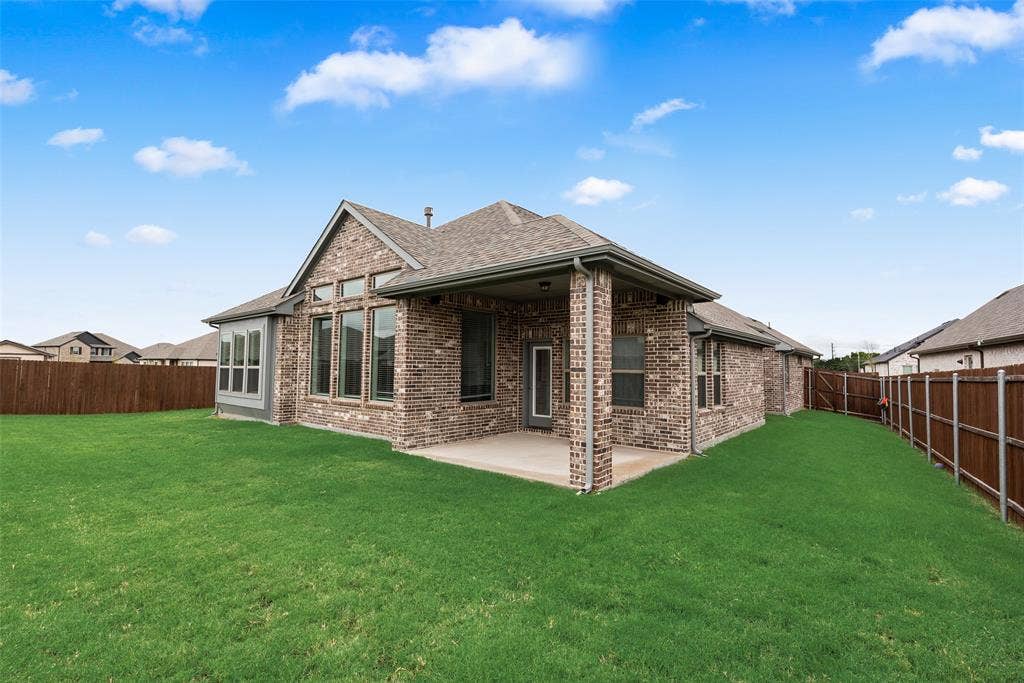 107 White Sands Lane, Forney, TX 75126 Expansive green lawn with a wood fence, brick exterior, covered patio, and large windows