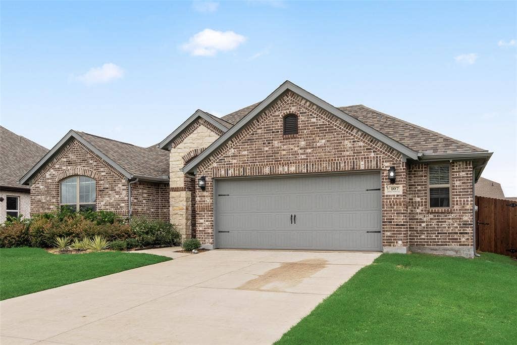 107 White Sands Lane, Forney, TX 75126 Brick facade, attached garage with a carriage-style door, concrete driveway, and established front landscaping