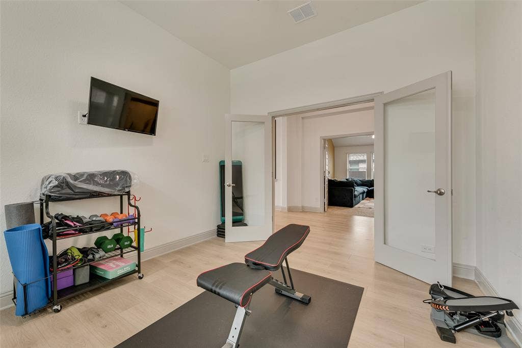 107 White Sands Lane, Forney, TX 75126 Enclosed study currently used as an exercise room, with double doors and wood-finish flooring
