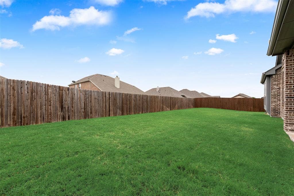 107 White Sands Lane, Forney, TX 75126 Expansive grassy yard area with a wood privacy fence and brick exterior