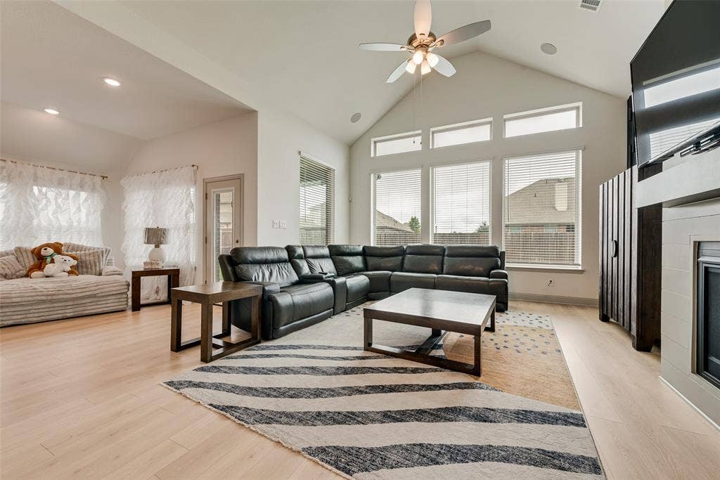 107 White Sands Lane, Forney, TX 75126 Vaulted ceiling with recessed lighting, light wood-finish flooring, multiple large windows, ceiling fan with integrated lighting, and a built-in fireplace