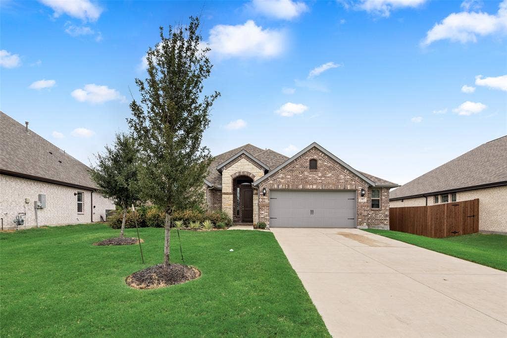 107 White Sands Lane, Forney, TX 75126 Brick facade with a covered entry, attached garage with a carriage-style door, concrete driveway, and manicured lawn