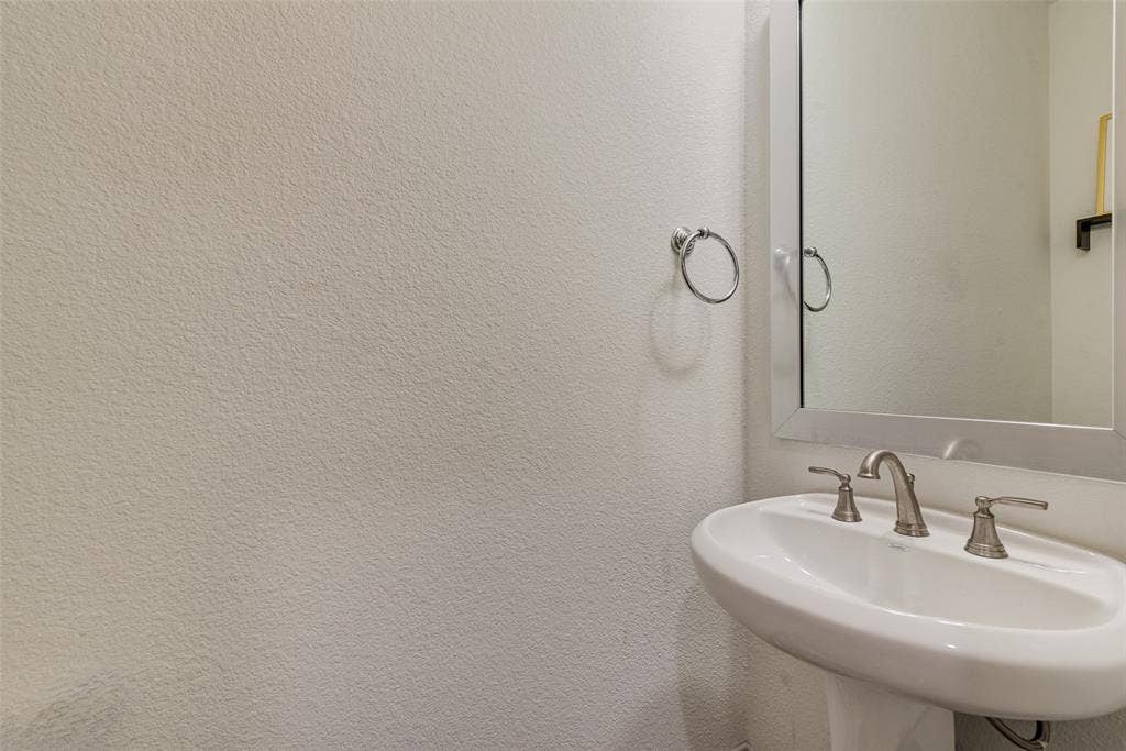107 White Sands Lane, Forney, TX 75126 Half bathroom with a pedestal sink, two-handle faucet, and wall mirror