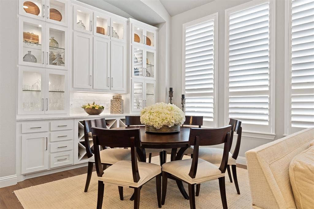9716 Wilderness Road, Little Elm, TX 75068 Dining room with built-in white cabinetry with glass display fronts, integrated wine storage.