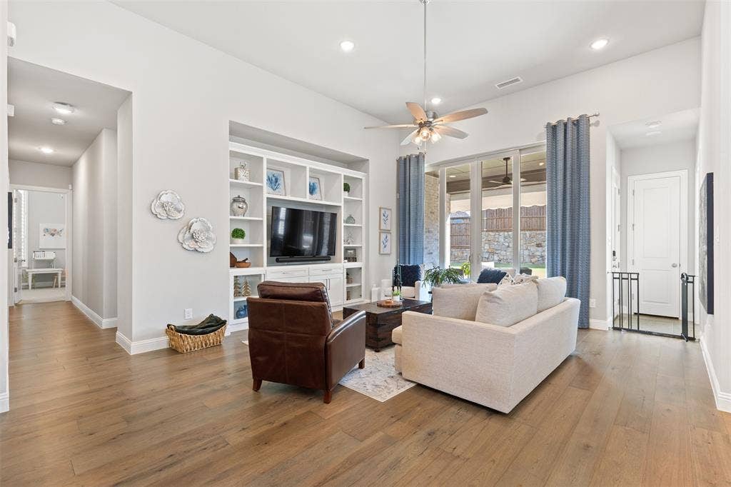 9716 Wilderness Road, Little Elm, TX 75068 Living room with integrated built-in cabinetry, wood-finish flooring, recessed lighting, and large sliding glass doors