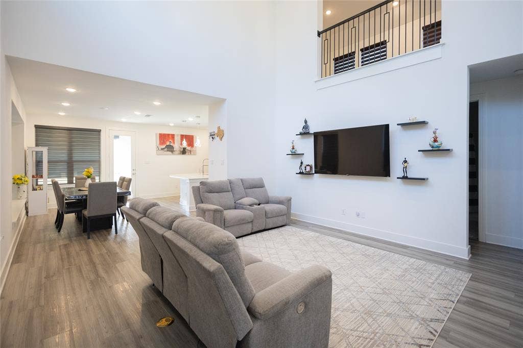 3017 Andorra Road, McKinney, TX 75071 Double-height living area with wood-finish flooring, recessed lighting, and an open concept layout