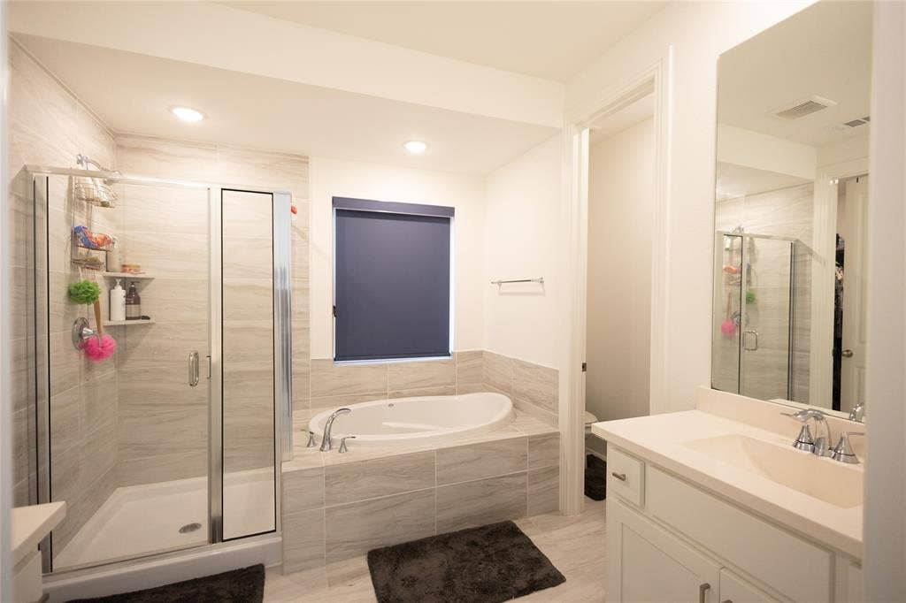 3017 Andorra Road, McKinney, TX 75071 Walk-in shower with clear glass enclosure, a built-in soaking tub, a single vanity with an integrated sink, and a rectangular wall-mounted mirror