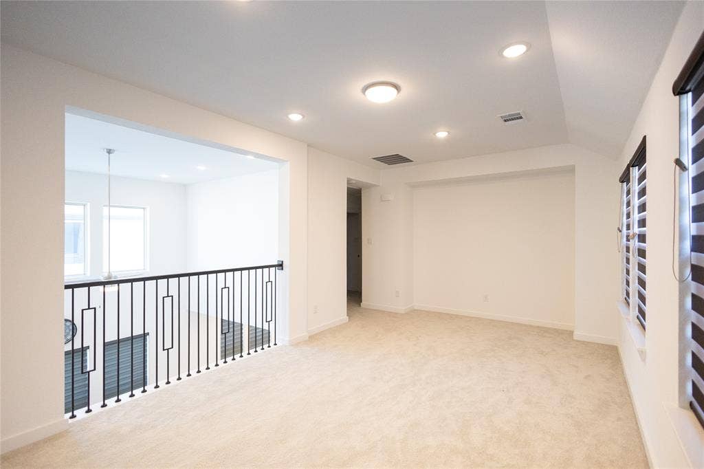 3017 Andorra Road, McKinney, TX 75071 Spacious loft-style room featuring light-finish wood flooring, recessed ceiling lighting, and a modern metal railing system overlooking a lower level