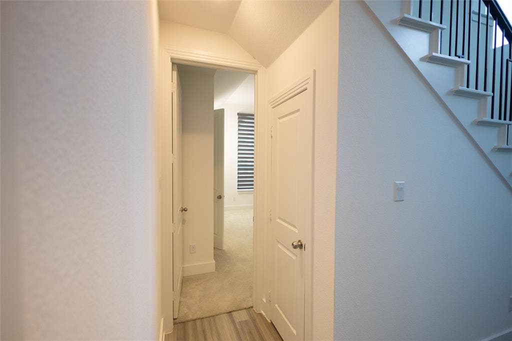 3017 Andorra Road, McKinney, TX 75071 Wood-finish flooring with white baseboards, white interior doors with satin nickel hardware, and a staircase featuring white treads and risers with black balusters