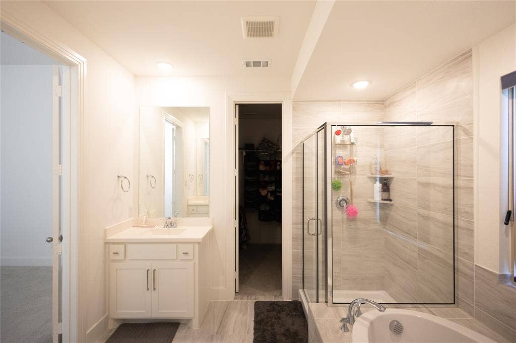 3017 Andorra Road, McKinney, TX 75071 White vanity with a single sink, walk-in shower with glass enclosure, white soaking tub, and tiled flooring
