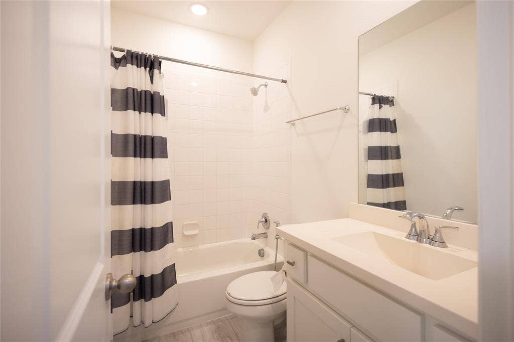 3017 Andorra Road, McKinney, TX 75071 Bathroom featuring a built-in tub with shower, white subway tile surround, single vanity with integrated sink, chrome fixtures, and wood-finish flooring