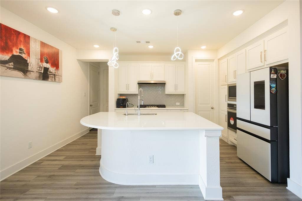 3017 Andorra Road, McKinney, TX 75071 Kitchen featuring a large central island, white cabinetry, a built-in refrigerator, and wood-finish flooring