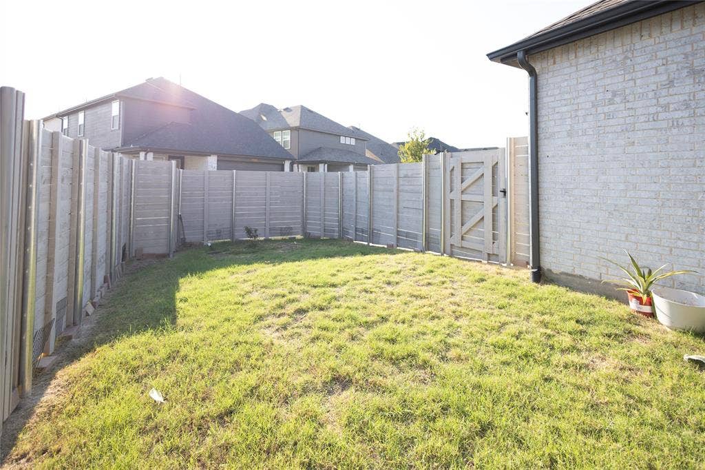 3017 Andorra Road, McKinney, TX 75071 Fenced backyard with light gray brick exterior, wood privacy fence, and a wooden gate
