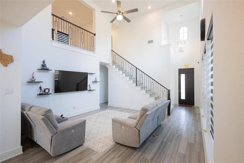 3017 Andorra Road, McKinney, TX 75071 Soaring ceilings, wood-finish flooring, and a contemporary open-tread staircase with black wrought iron railings