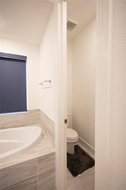 3017 Andorra Road, McKinney, TX 75071 Soaking tub with tile surround, partial wall, and recessed toilet area