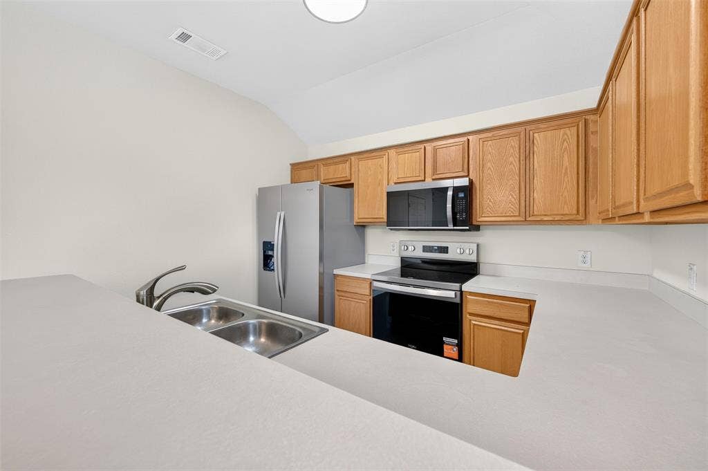 2724 Douglas Drive, McKinney, TX 75071 Kitchen featuring new stainless steel appliances, light wood-finish cabinetry, a double basin sink