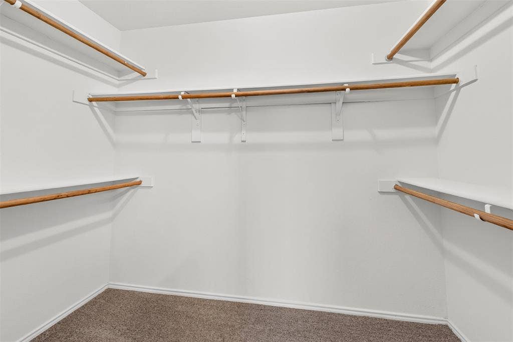 2724 Douglas Drive, McKinney, TX 75071 Spacious closet with multiple shelving levels and hanging rods, complemented by soft carpet flooring