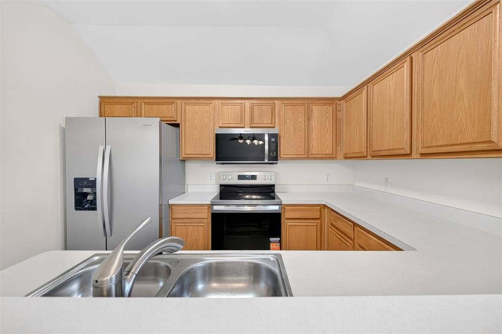 2724 Douglas Drive, McKinney, TX 75071 Kitchen featuring light wood cabinetry, a stainless steel double basin sink with a brushed nickel faucet, light-colored countertops, and new stainless steel appliances