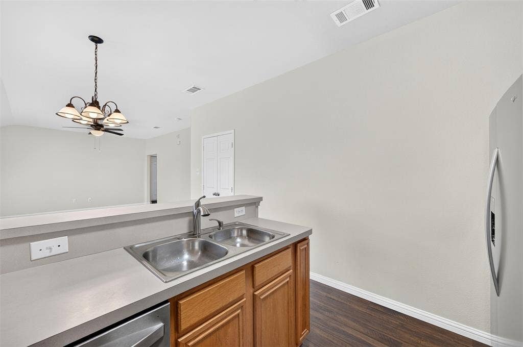 2724 Douglas Drive, McKinney, TX 75071 Stainless steel double basin sink, chrome faucet, dishwasher and light wood-finish cabinetry.