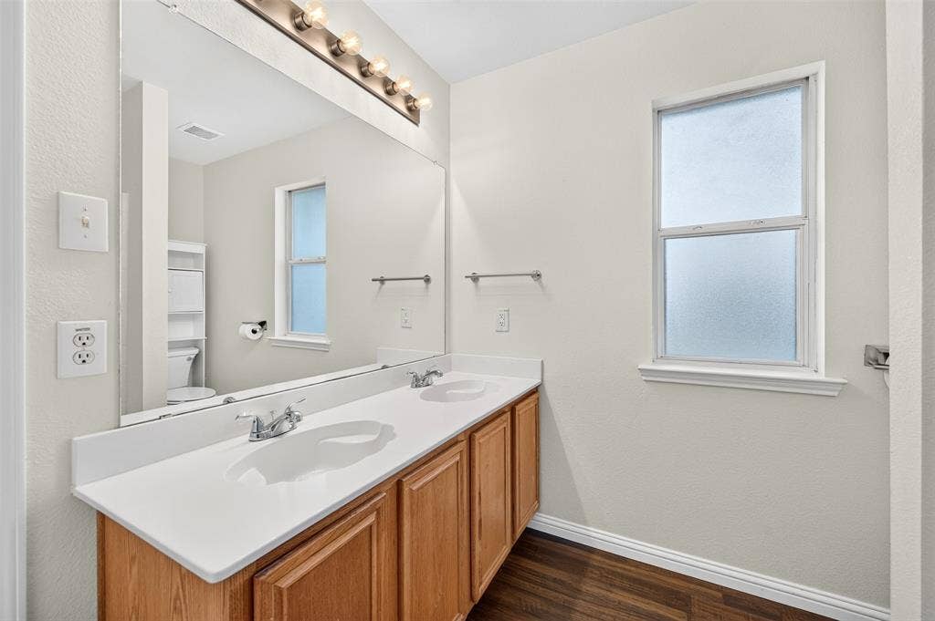 2724 Douglas Drive, McKinney, TX 75071 Double vanity with white countertops, wood-finish vanity cabinet and chrome fixtures