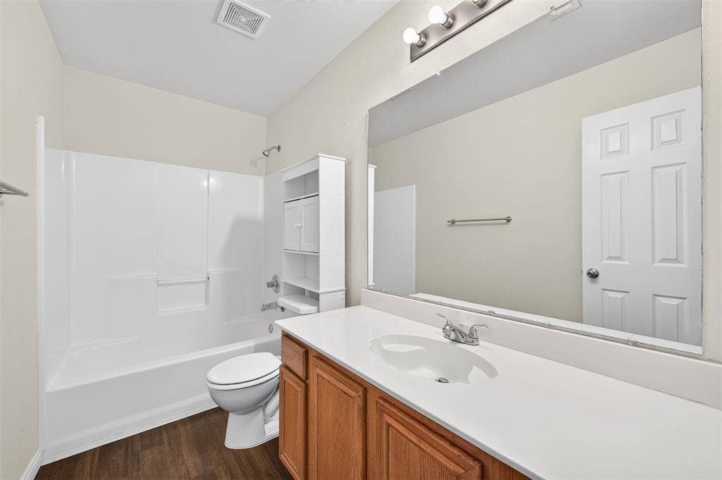 2724 Douglas Drive, McKinney, TX 75071 Wood-finish LVP flooring with a white tub and shower combo