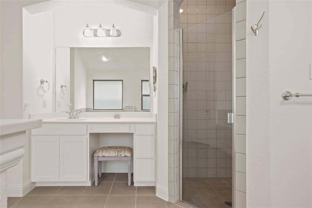 6152 Cobbetts Pond Lane, Fort Worth, TX 76179 Bathroom vanity with integrated sink, three-light vanity bar, frameless mirror, and adjacent glass-enclosed shower with tile surround