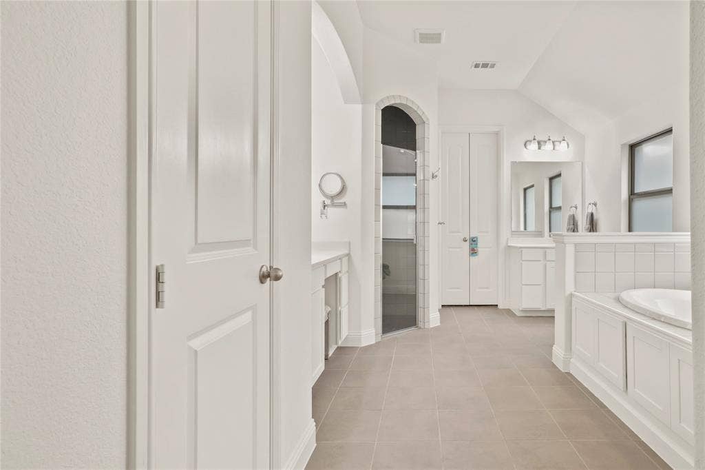6152 Cobbetts Pond Lane, Fort Worth, TX 76179 Spacious bathroom with neutral tile flooring, dual vanities, built-in soaking tub, and a glass-enclosed shower