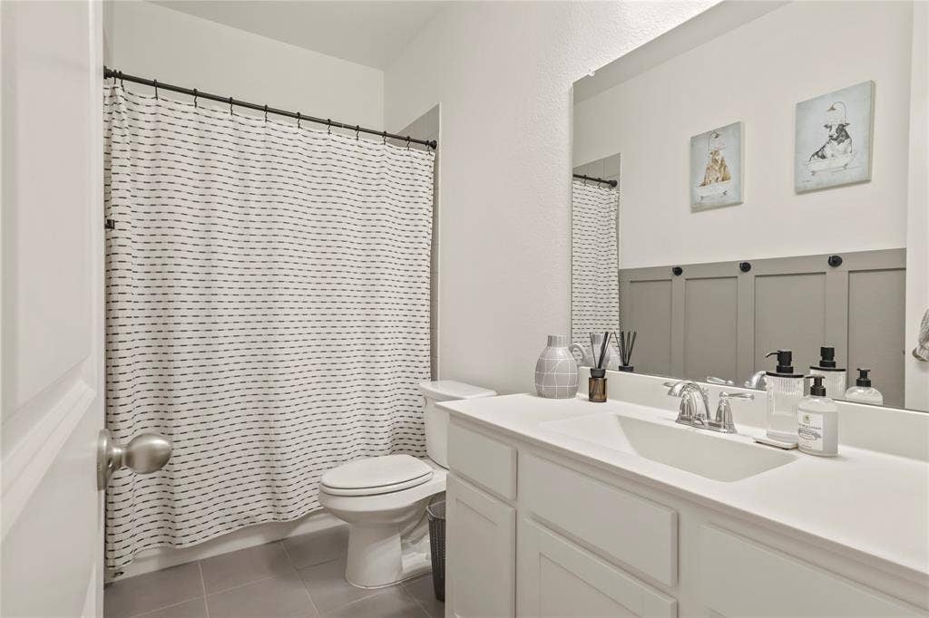 6152 Cobbetts Pond Lane, Fort Worth, TX 76179 Bathroom featuring a white vanity with an integrated sink, polished chrome faucet, oversized mirror, and gray tiled flooring