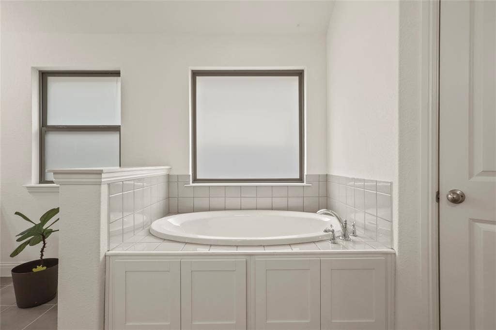 6152 Cobbetts Pond Lane, Fort Worth, TX 76179 Built-in soaking tub with tile surround, framed by two windows and featuring chrome fixtures