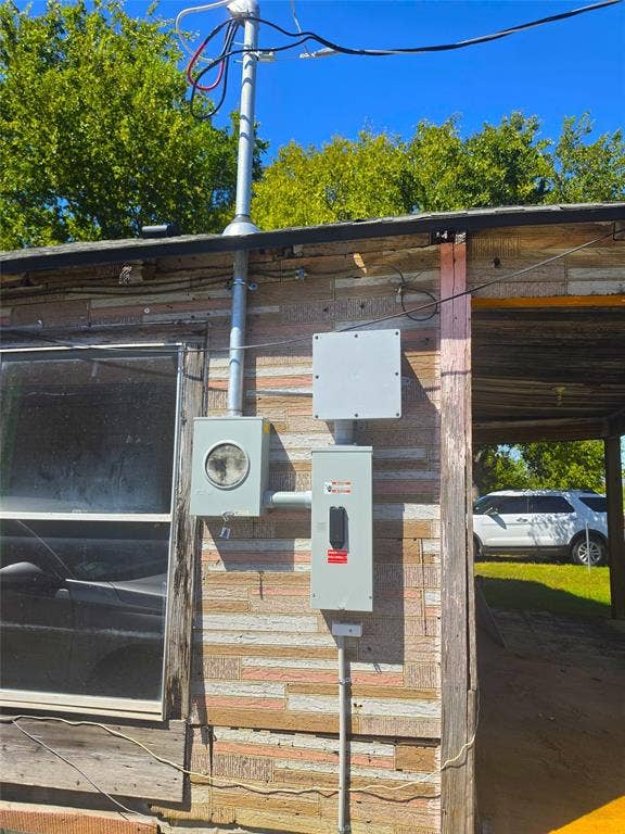 610 S Falls Street, Mart, TX 76664 Electrical service entrance with conduit and meter box, mounted on exterior wall with textured paneling and window