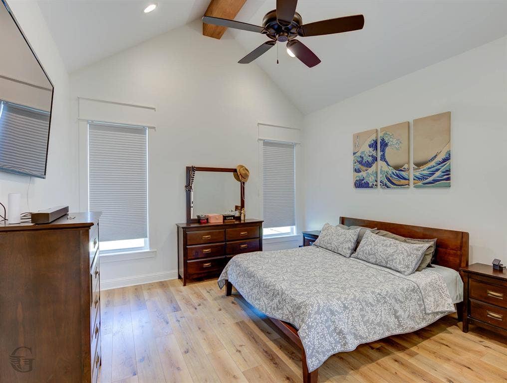 Vaulted ceiling with exposed wood beam, wood-finish flooring, recessed lighting, and dual windows with blinds