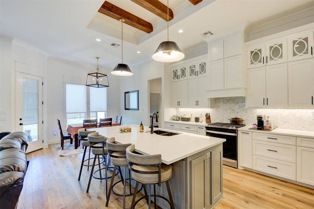 Gourmet kitchen with wood-finish flooring, white cabinetry, a large kitchen island with counter seating, and recessed lighting