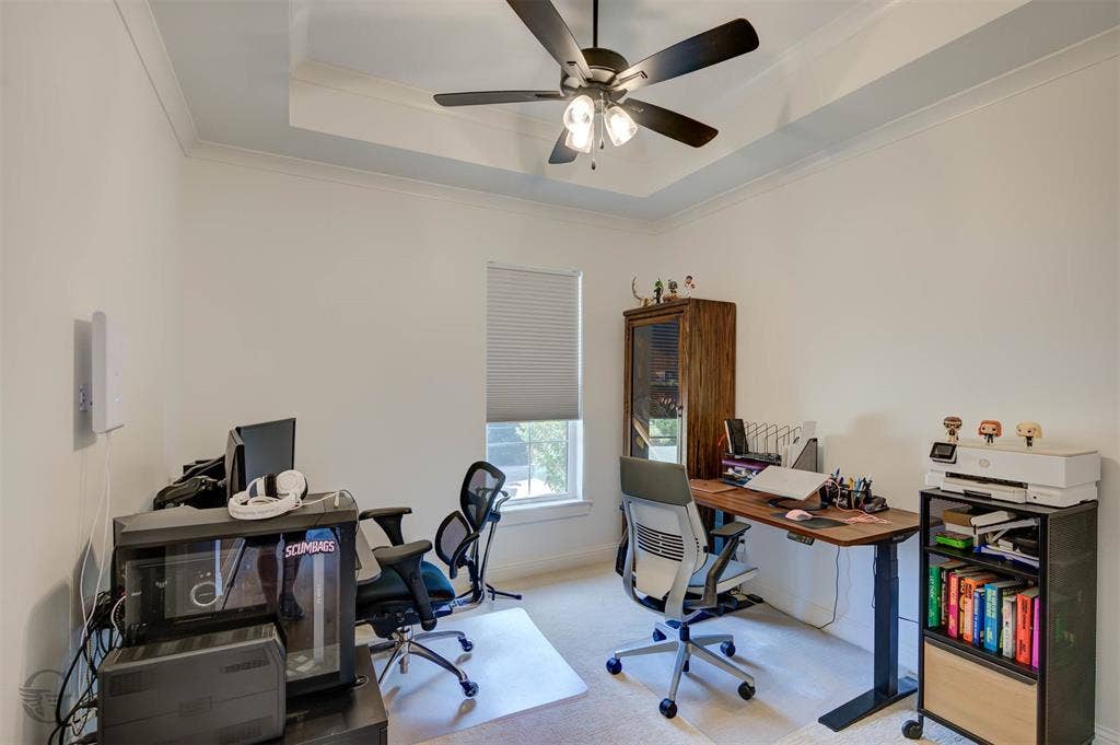 Tray ceiling with crown molding, ceiling fan, carpeted flooring, and a single window with blinds