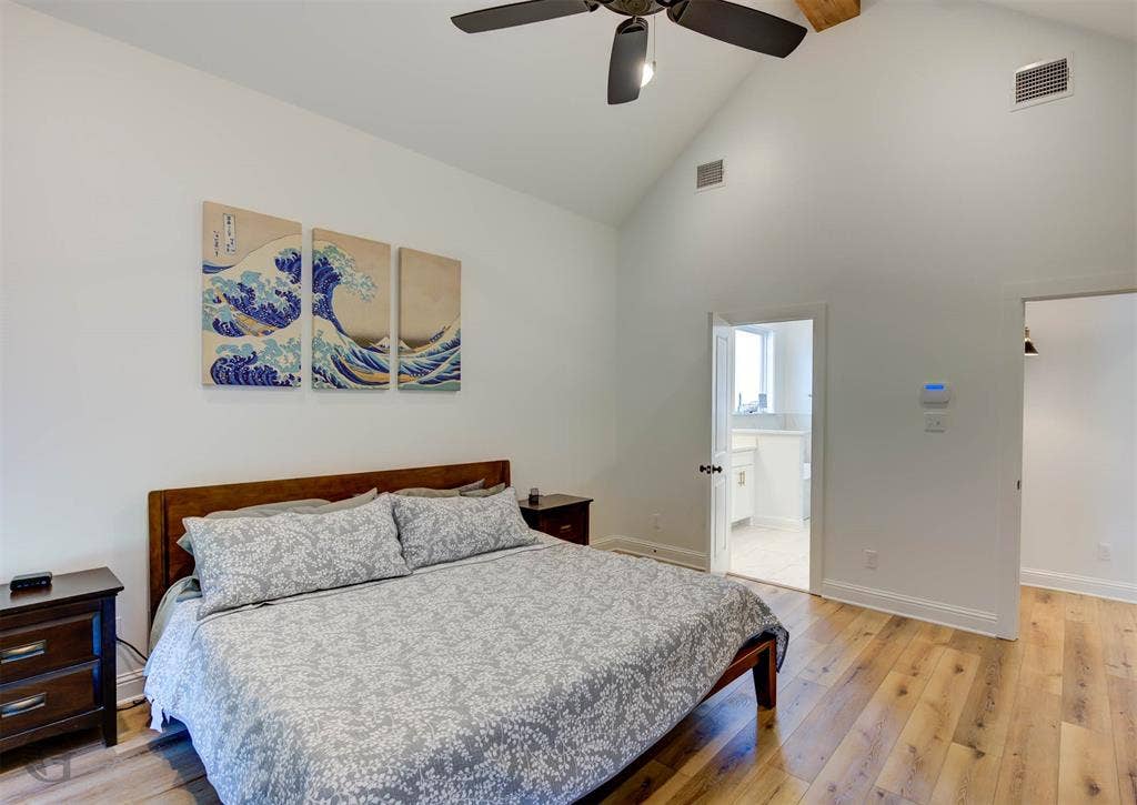 Vaulted ceiling, wood-finish flooring, ceiling fan, and white walls