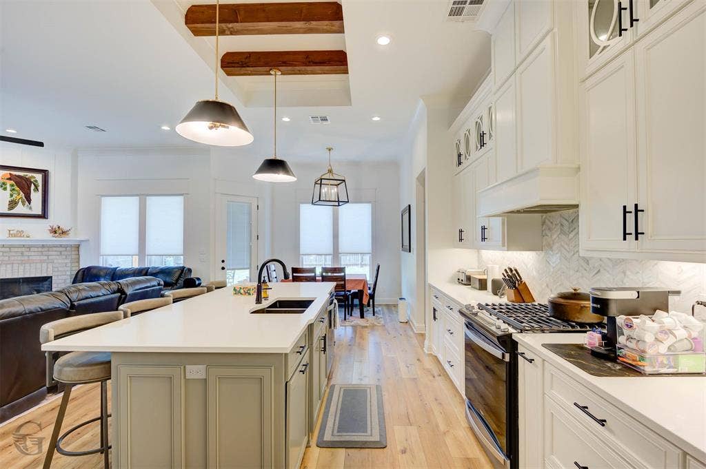 Open-concept living area with wood-finish flooring, exposed ceiling beams, and recessed lighting
