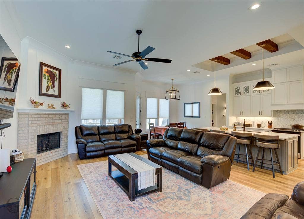 Open-concept living area featuring wood-finish flooring, a brick fireplace, and recessed lighting