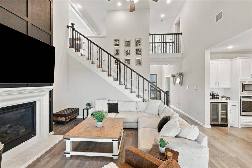 Two-story living area with a fireplace, wood-finish flooring, and a second-story balcony