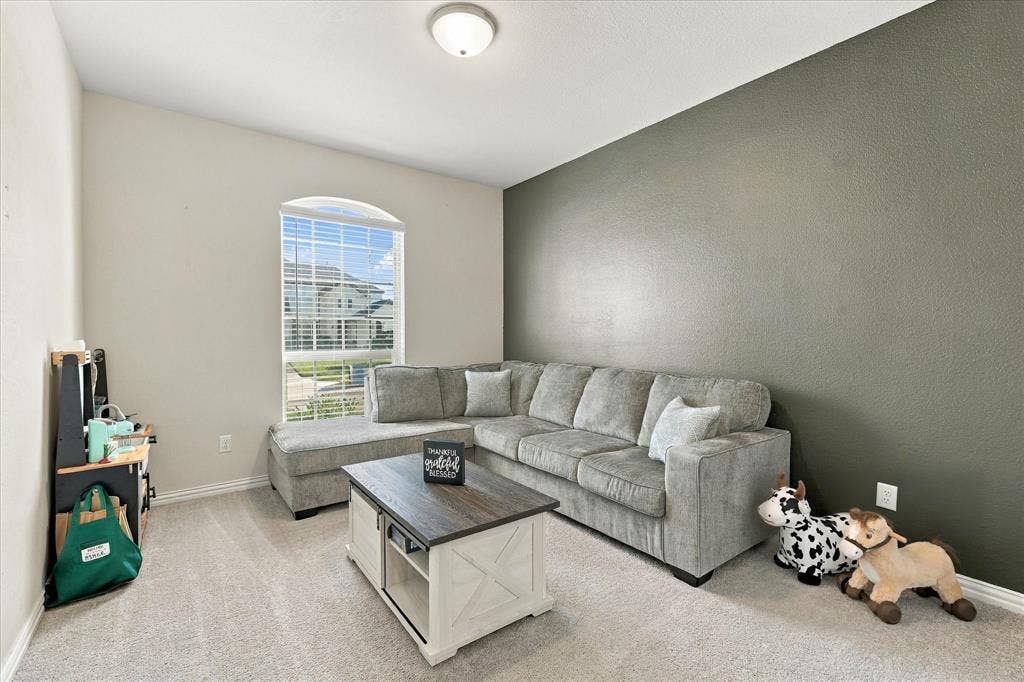 Vaulted ceiling, arched window with blinds, accent wall, and light-toned carpeting