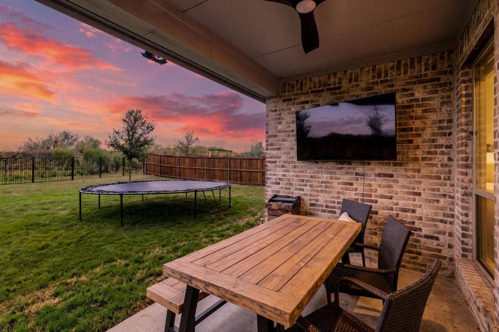 Covered patio featuring a ceiling fan, brick accent wall, and concrete flooring