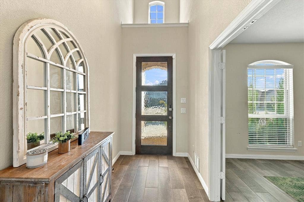 Wood-finish flooring throughout, frosted glass entry door, and an arched transom window