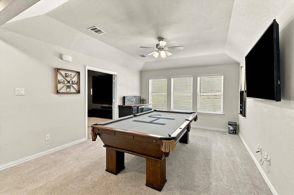 Sloped ceiling accentuating the room's height, plush carpet flooring, recessed lighting, and three panel windows with horizontal blinds