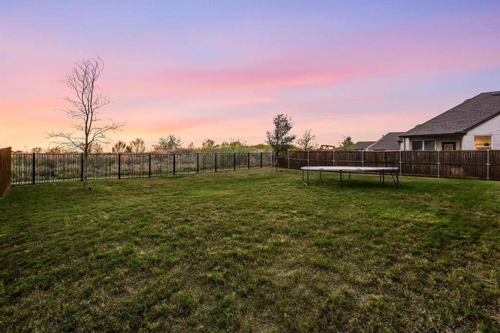 Expansive green lawn with a wood fence and a black metal fence