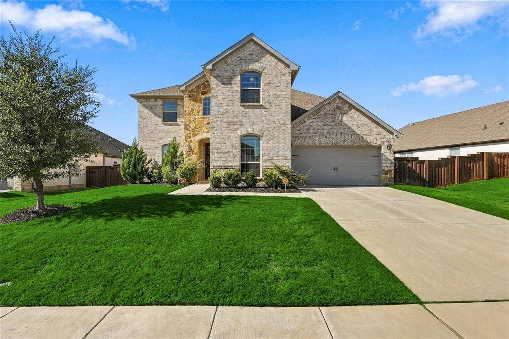 Two-story residence featuring a brick and stone facade, arched entry, and an attached two-car garage
