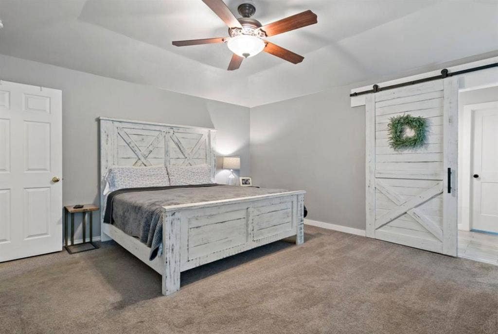 1603 Vicksburg Drive, Sachse, TX 75048 Carpeted bedroom with a barn door, baseboards, and a ceiling fan