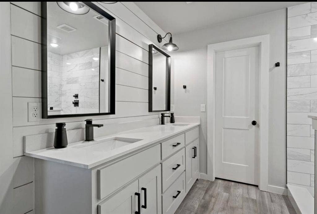 1603 Vicksburg Drive, Sachse, TX 75048 Bathroom featuring double vanity, wood finished floors, tiled shower, and a sink